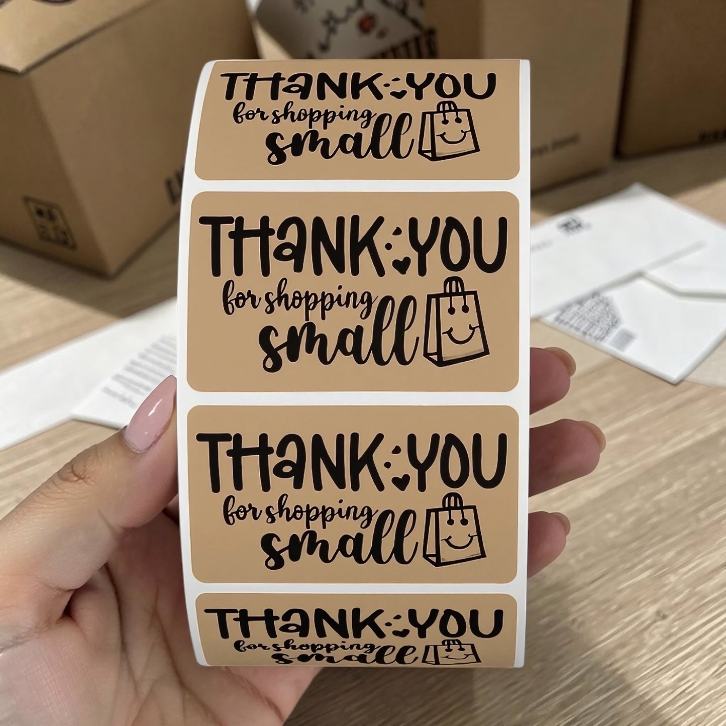 Thank You for Shopping Small kraft sticker roll held in hand with shipping boxes in background