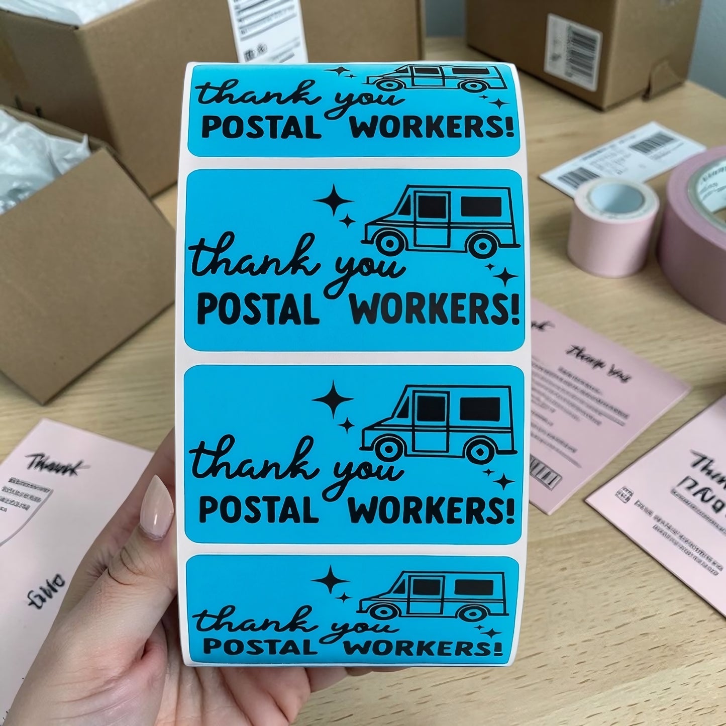Thank You Postal Workers blue sticker being applied to kraft gift box with flowers