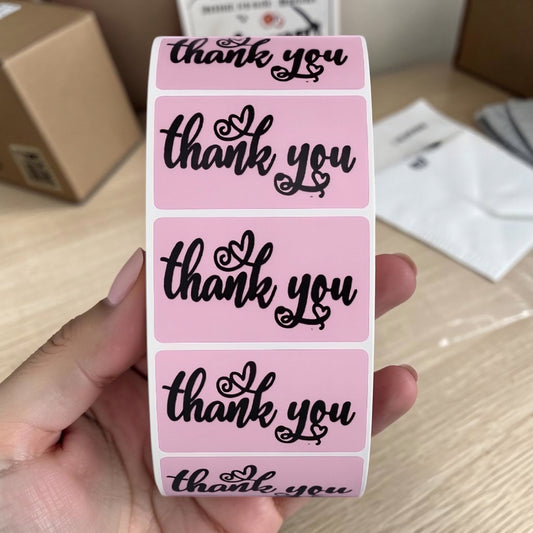 Pink Thank You rectangle sticker roll held in hand